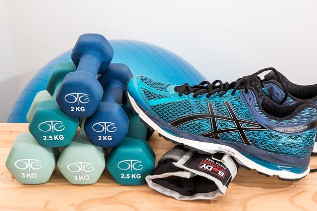 Parcstone Apartments in Fayetteville A pair of Asics shoes and a pair of dumbbells are displayed on a wooden table.