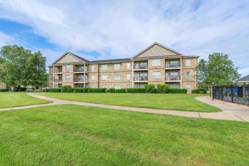 Apartments in Fayetteville, North Carolina Three-story brick apartment building with balconies, surrounded by green lawns and a few trees under a cloudy blue sky. Parcstone Apartments For Rent in Fayetteville