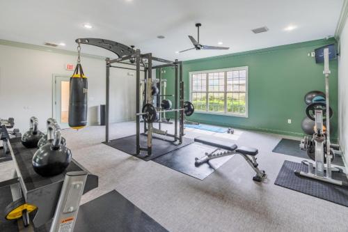 Apartments in Fayetteville, North Carolina A gym with weightlifting equipment, a punching bag, exercise bikes, and a bench, set against a green and white interior with a window. Parcstone Apartments For Rent in Fayetteville