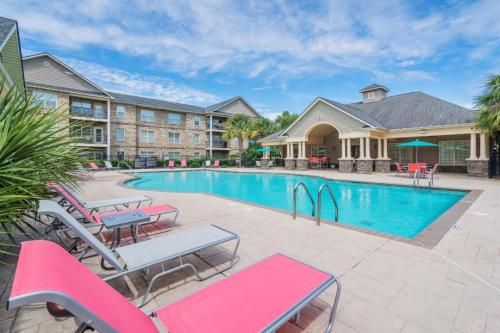 Apartments in Fayetteville, North Carolina Outdoor pool area with pink lounge chairs, surrounded by apartment buildings and a clubhouse. Parcstone Apartments For Rent in Fayetteville