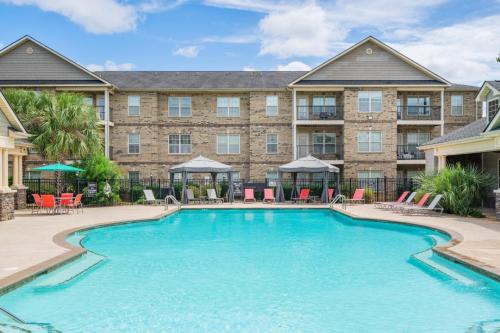 Apartments in Fayetteville, North Carolina Outdoor swimming pool with lounge chairs and cabanas, surrounded by a brick apartment building under a blue sky. Parcstone Apartments For Rent in Fayetteville