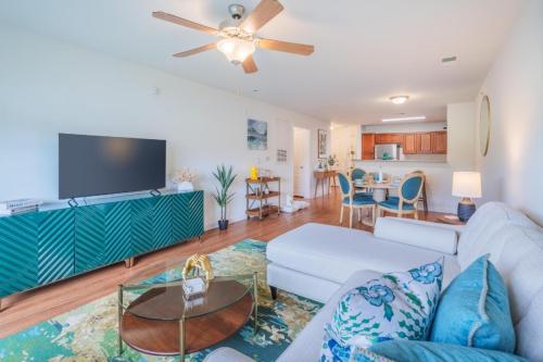 Apartments in Fayetteville, North Carolina A well-lit open living and dining area with a white sofa, glass coffee table, green TV stand, ceiling fan, and a dining table near a kitchen with wooden cabinets. Parcstone Apartments For Rent in Fayetteville