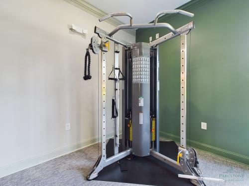 Apartments in Fayetteville, North Carolina A well-equipped home gym with a cable machine and pull-up bar in a room with green walls.